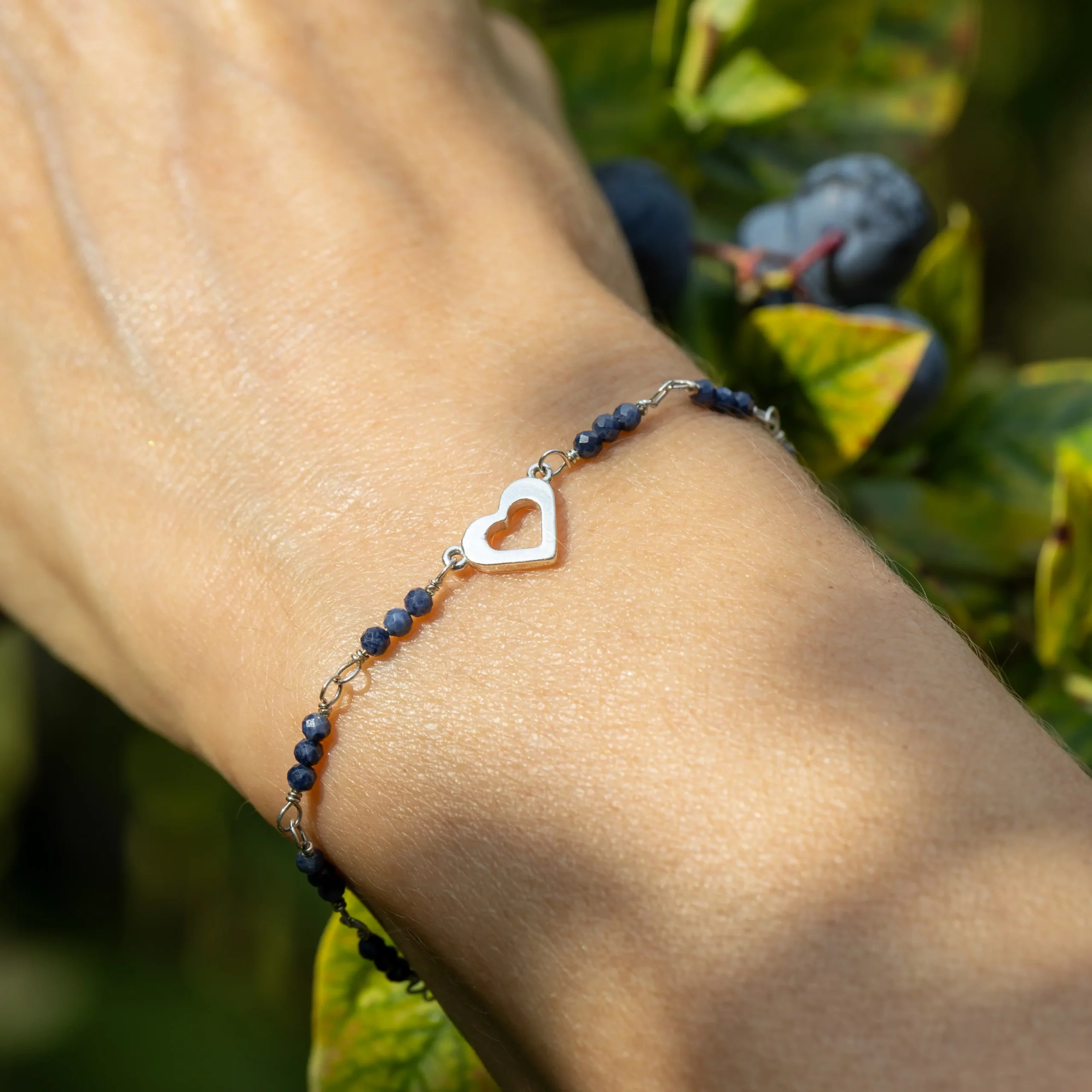 Srebrna bransoletka Serce z malutkimi szafirami na nadgarstku modelki.