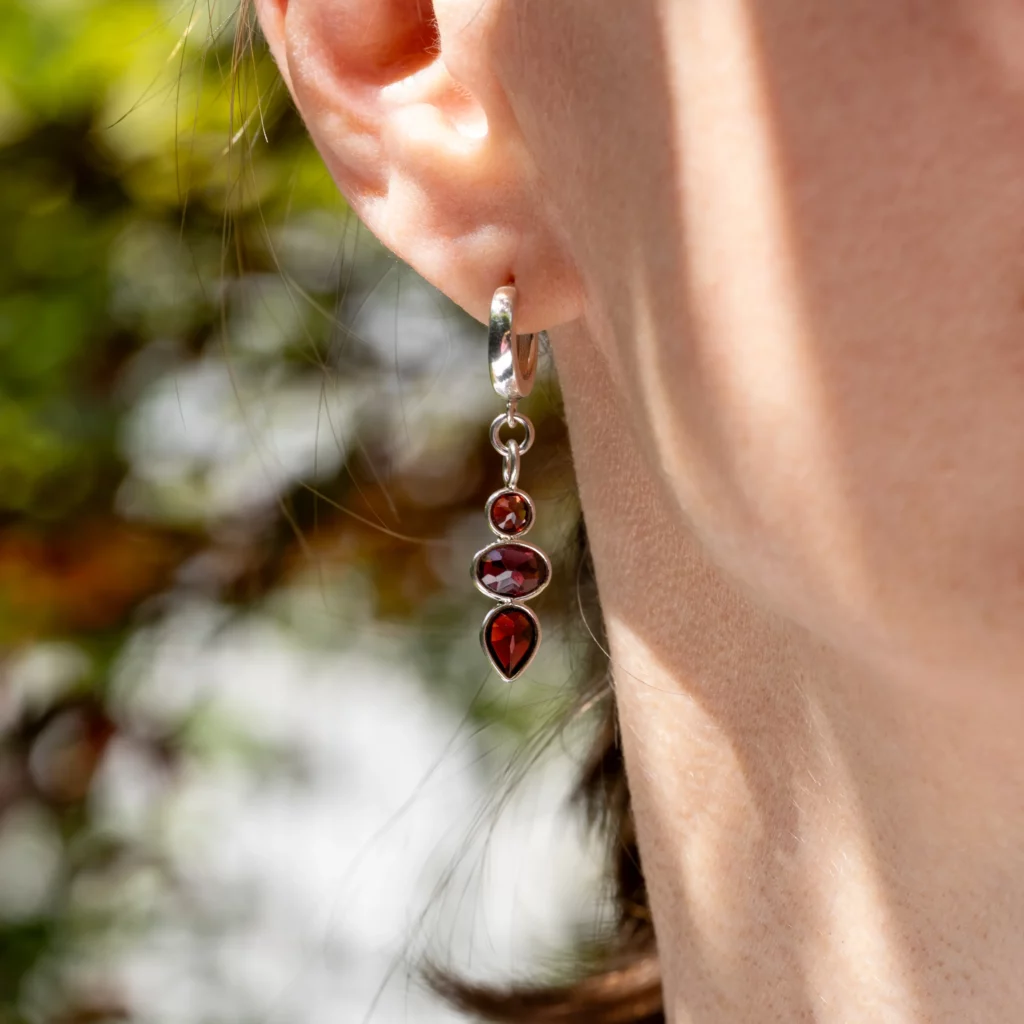 Kolczyki srebrne, wiszące z granatami z kolekcji Elegance na modelce.