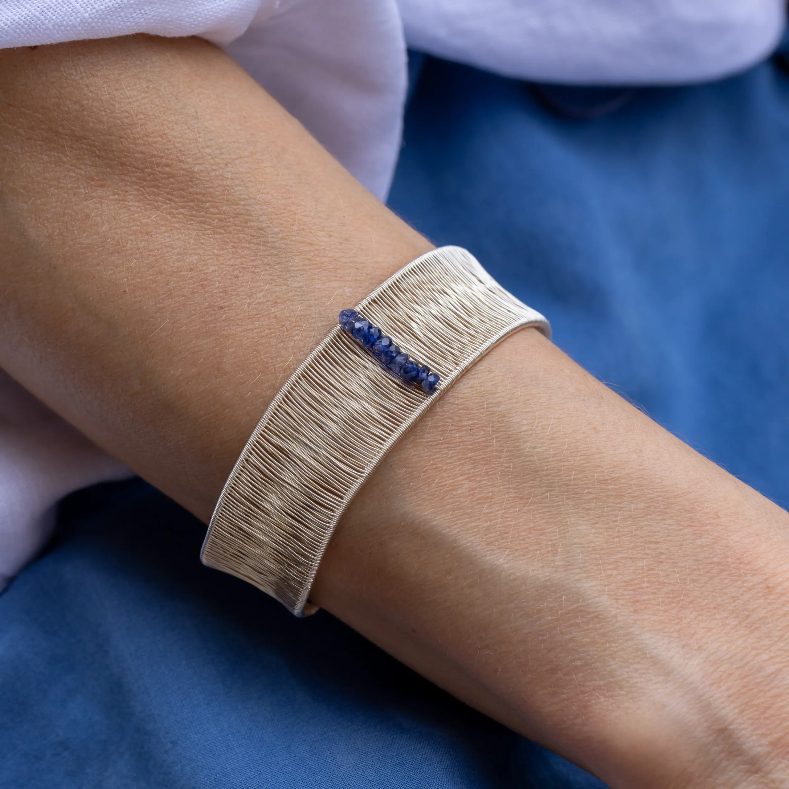 Bransoletka srebrna otwarta z kolekcji Alto z szafirami na modelce.