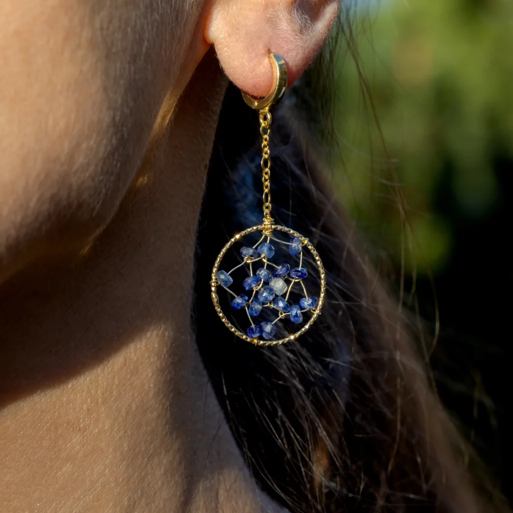 Pozłacane kolczyki srebrne z kolekcji Atrapaseños z granatowymi szafirami na modelce.