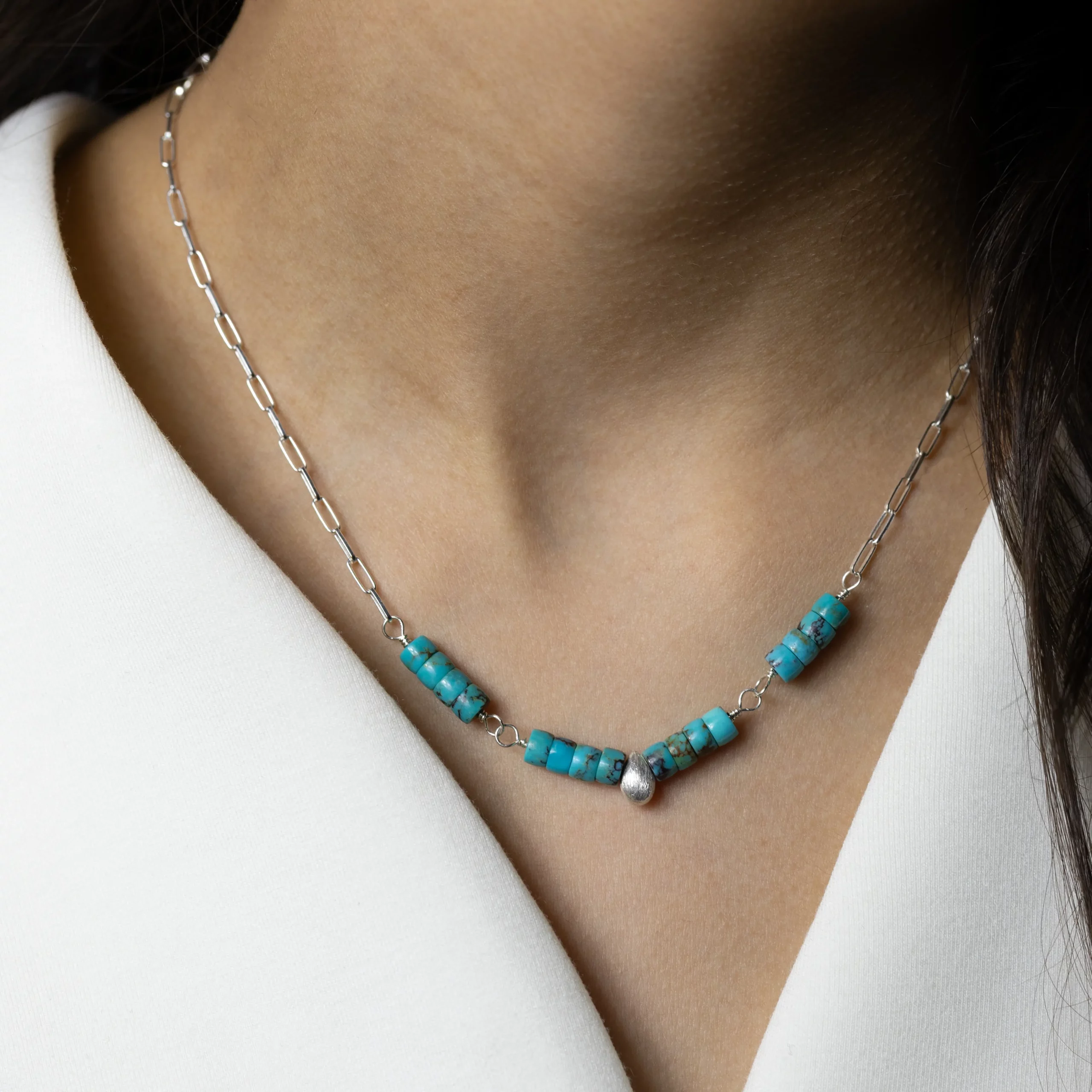 Srebrny naszyjnik Gota z pięknymi turkusami i srebrną łezką na modelce.