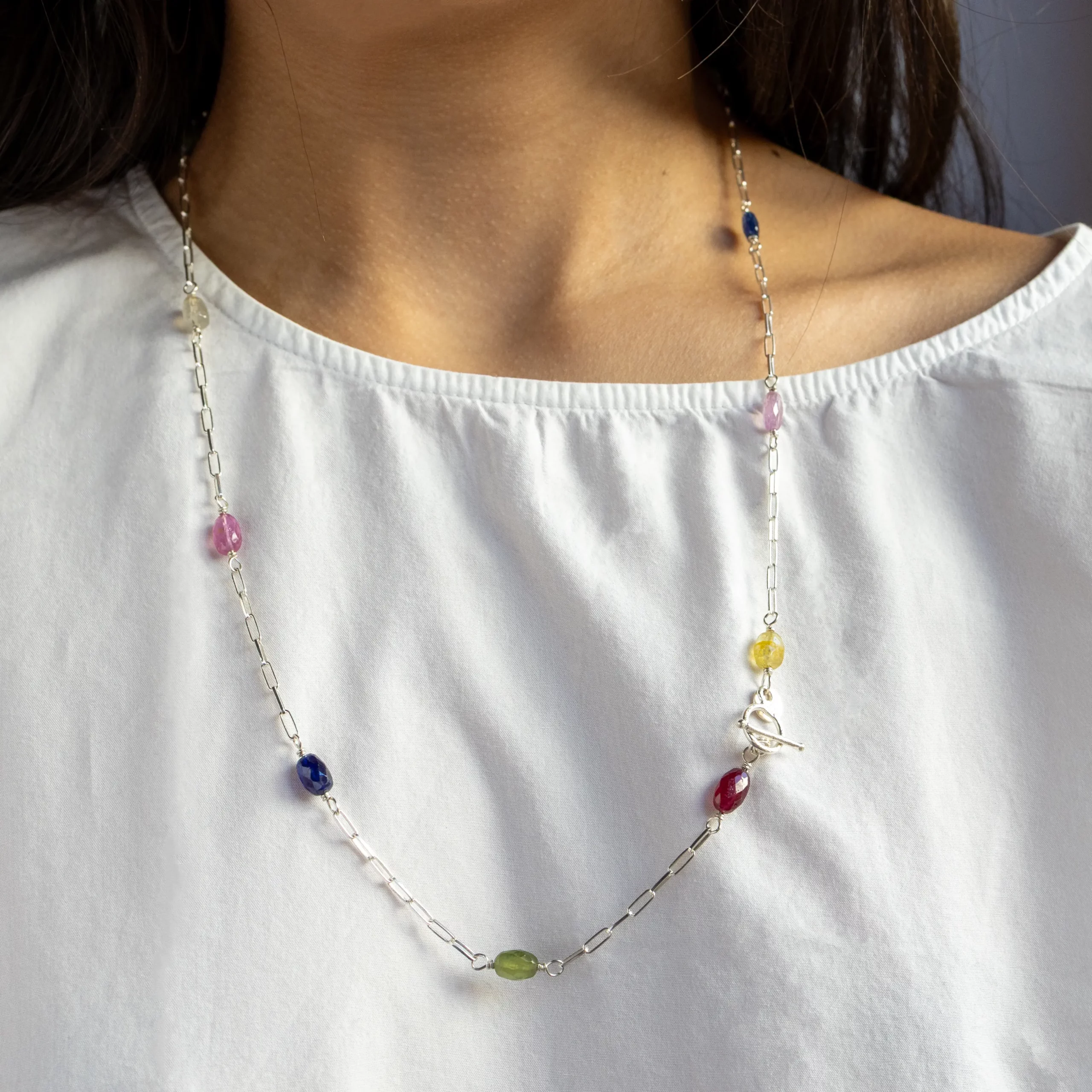 Naszyjnik długi, srebrny Lungo z kolorowymi szafirami i rubinami na modelce.