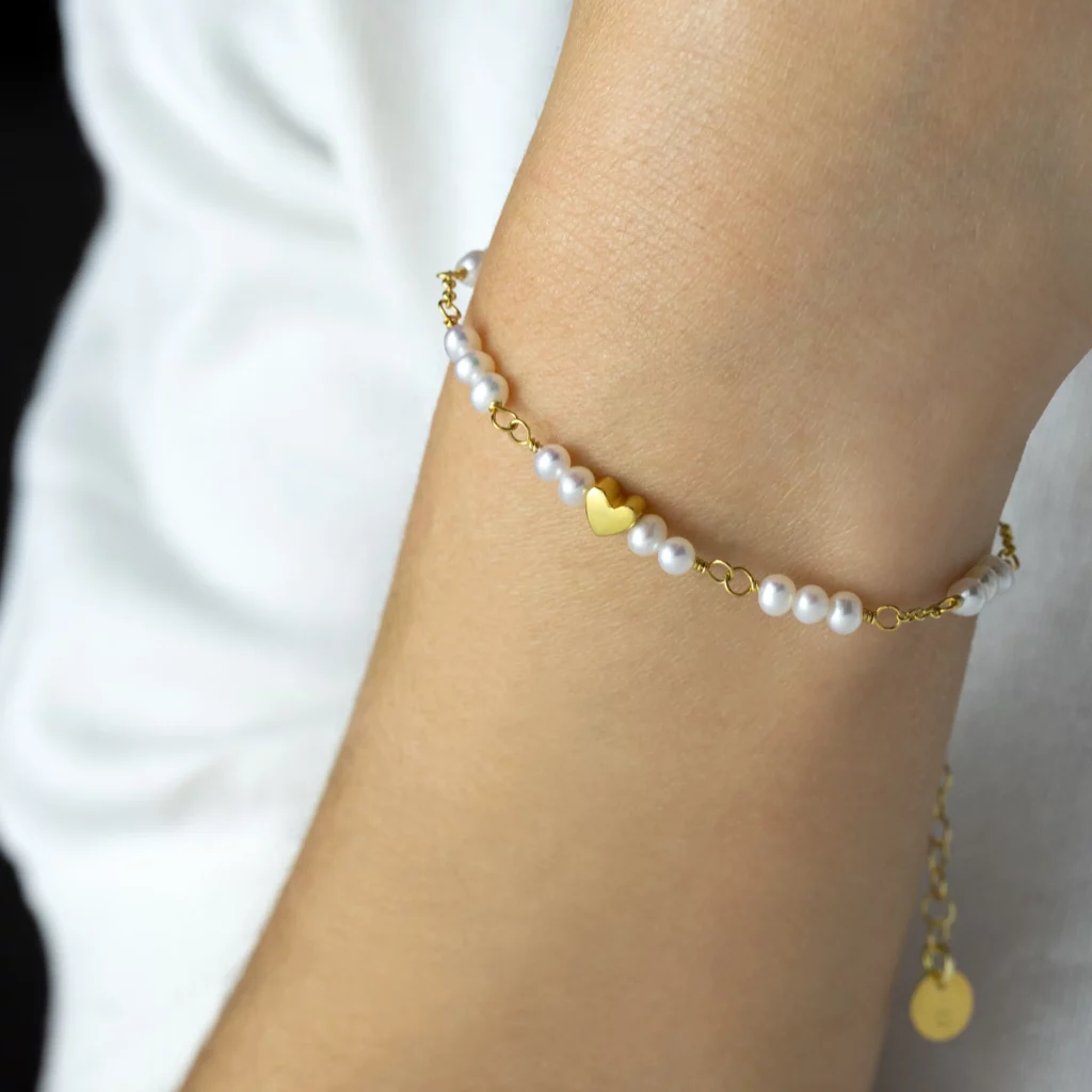 Bransoletka z pereł słodkowodnych i pozłacanego srebra z motywem serca na modelce.