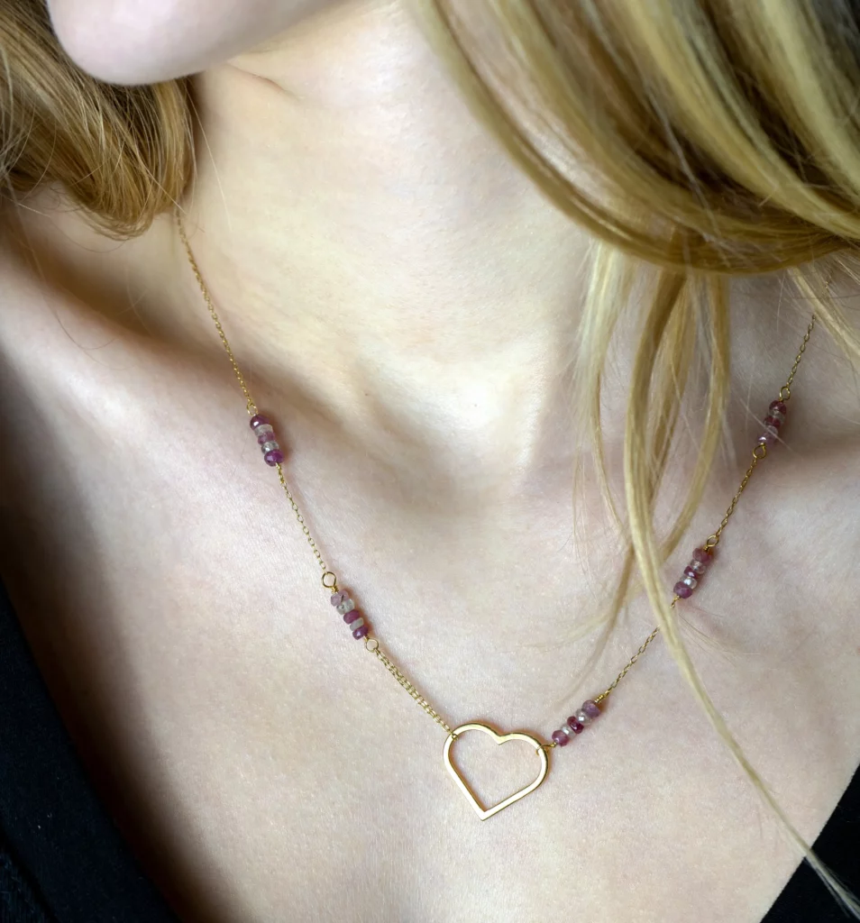 Elegancki pozłacany naszyjnik Serce II z rubinami i białymi szafirami na modelce.