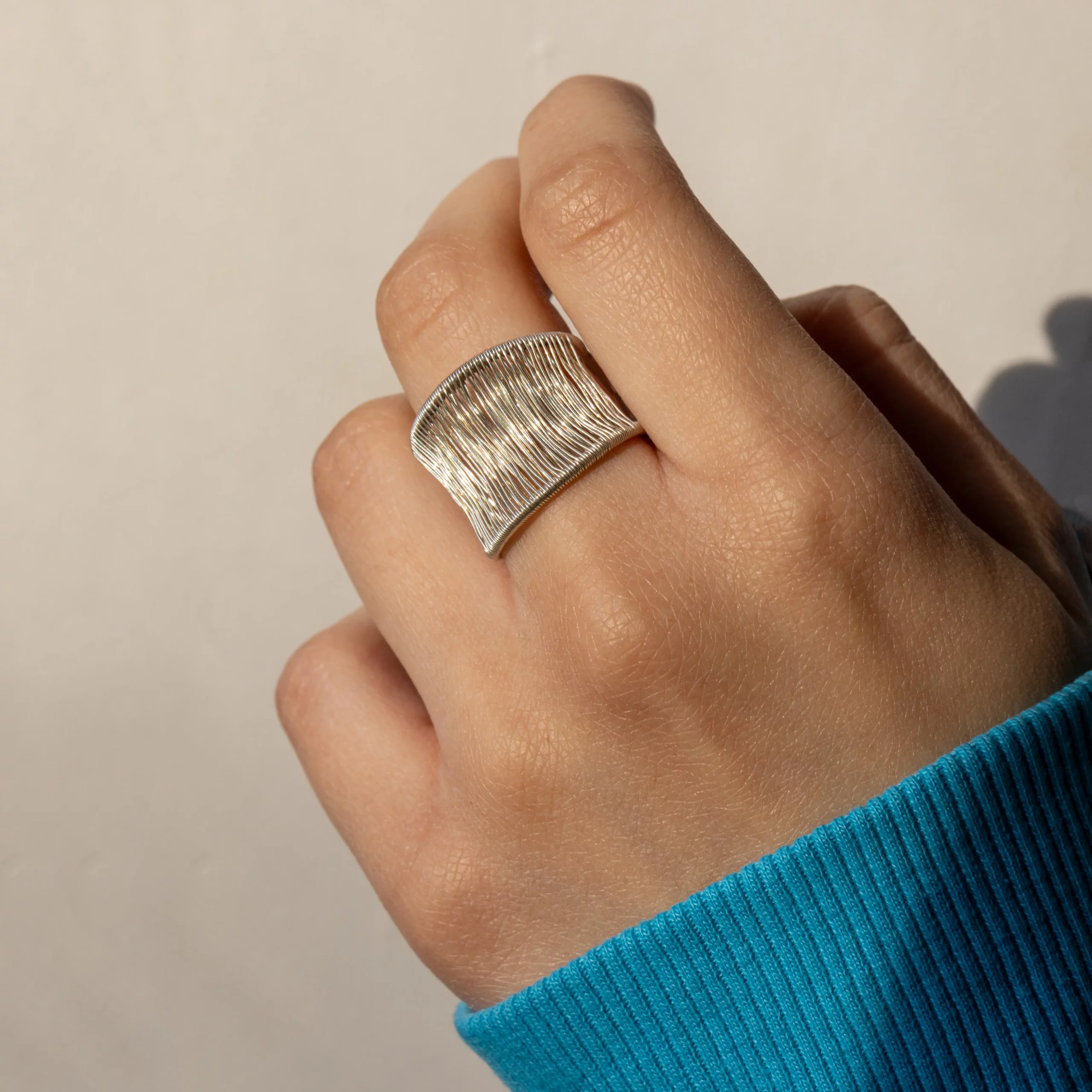 Srebrny pierścionek Alto Sauté wykonany ze srebra próby 925, wysoki, otwarty, z ręcznie oplecioną strukturą, prezentowany na dłoni