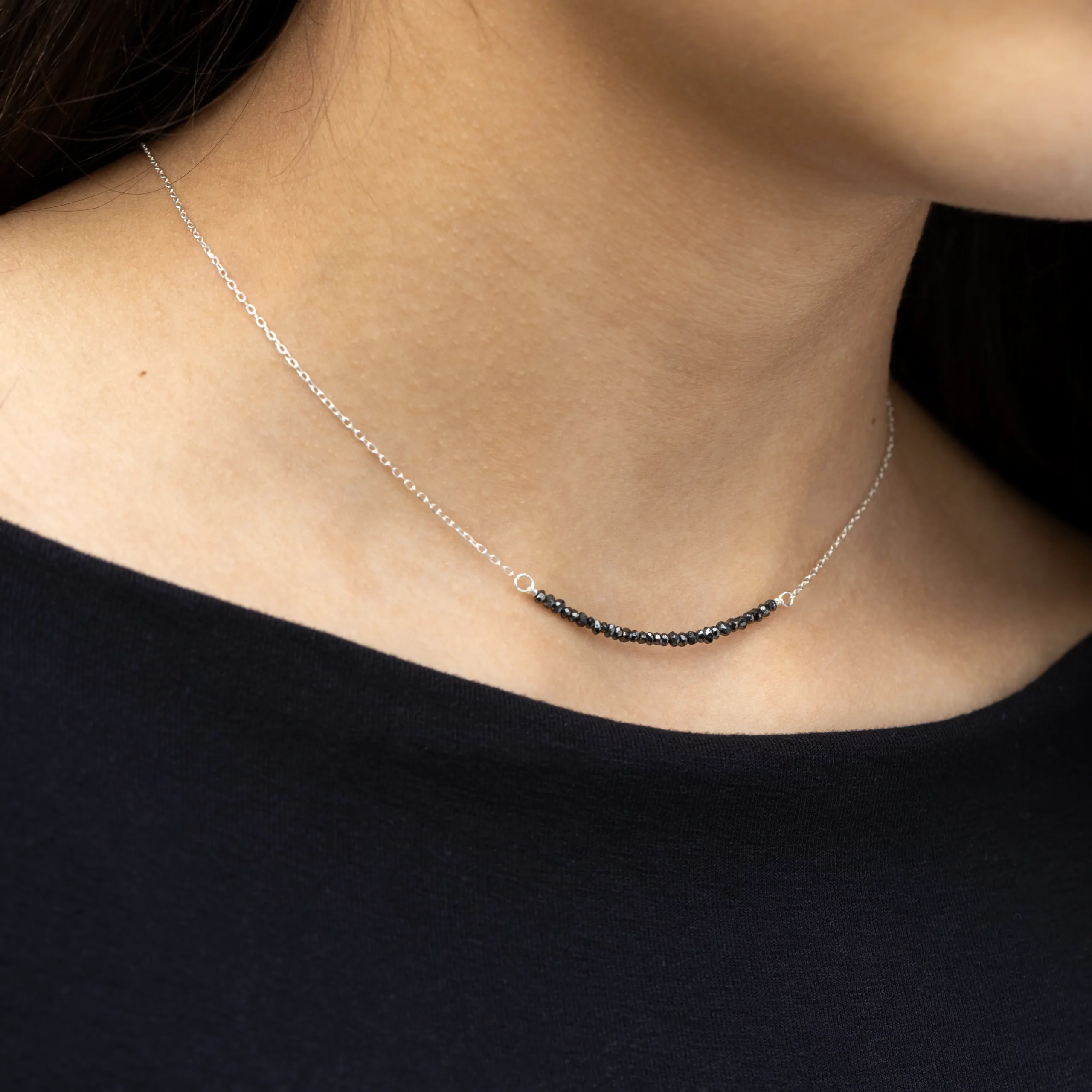 Srebrny naszyjnik Minimal Black Diamond z naturalnymi, szlifowanymi czarnymi diamentami na modelce.