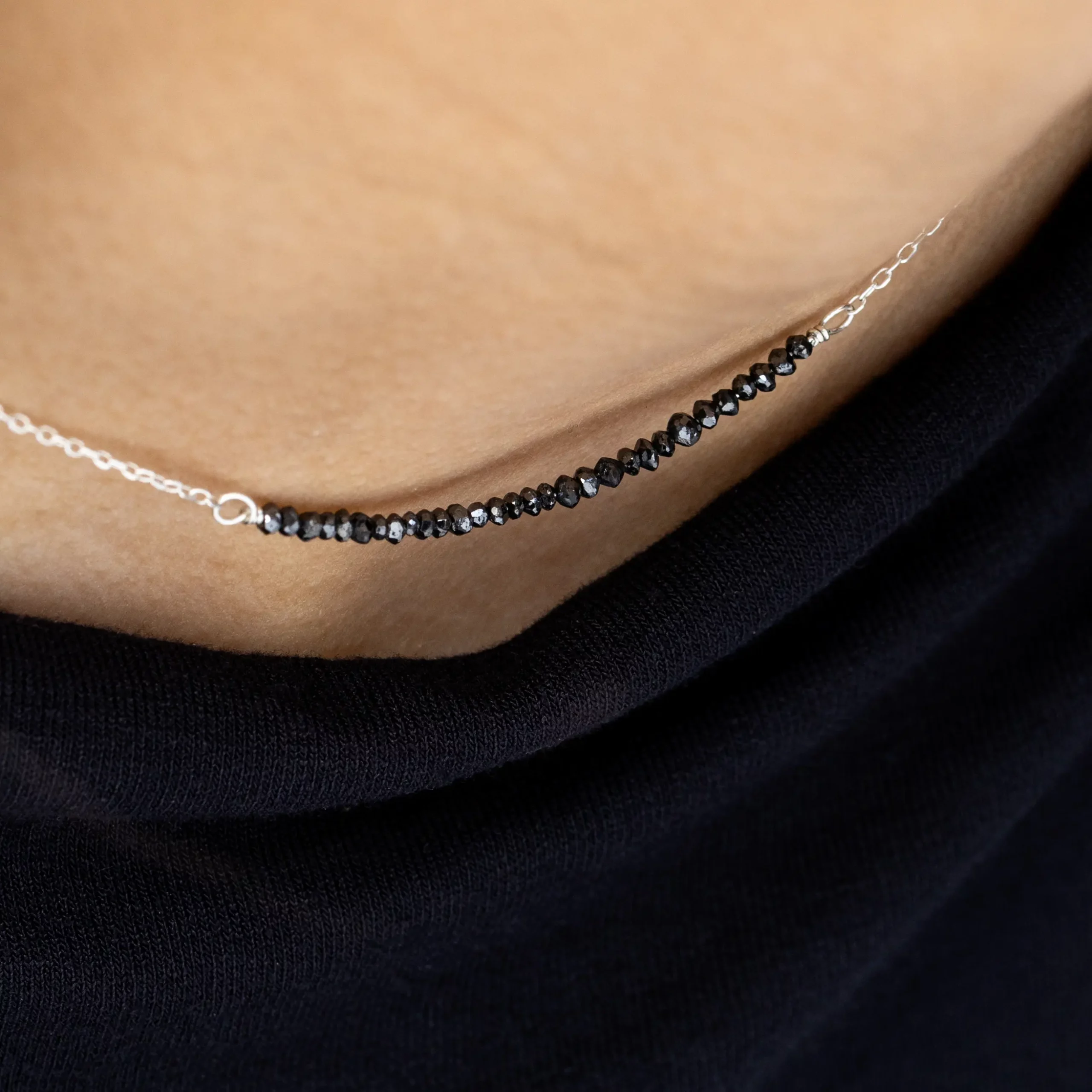 Detal czarnych diamentów naszyjnika srebrnego Minimal Black Diamond na modelce.